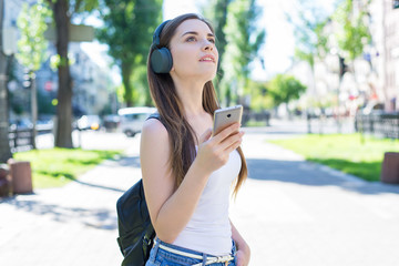 Modern tech technology gadget device education studying generation concept. Portrait of cheerful pensive dreamy lady holding using user cellular in hands holding black backpack park town background