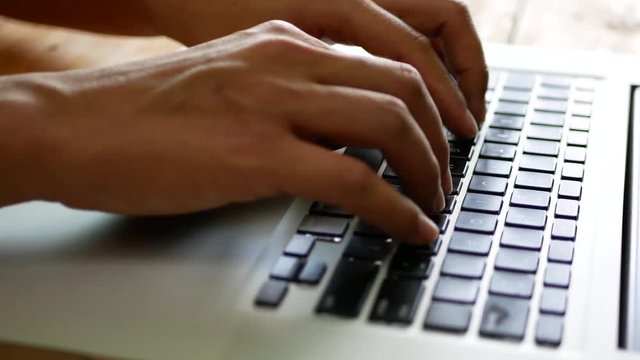 Selective focus of a man's hands typing / working on a keyboard of a laptop computer