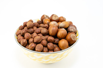 Group of hazelnuts in a bowl on white background