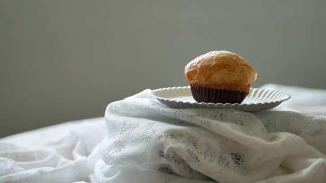 A cup bread in a paper plate rotating on a fluffy white cloth