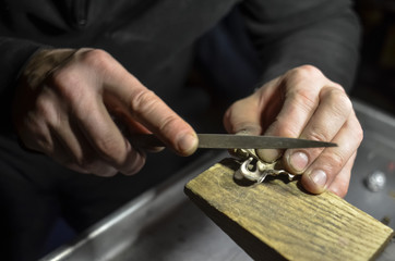 The master jeweler holds the working tool in his hands and makes jewelery at his workplace in the...