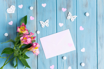 Mock up blank paper, mail envelope on a dark wooden background with natural flowers of white color and butterflies. Blank, frame for text. Greeting card design with flowers. Aalstroemeria