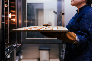 close up view of woman holding holding rack of sweets in a bakery.
