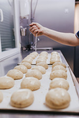 woman in bakery preparing sweets adding sugar.