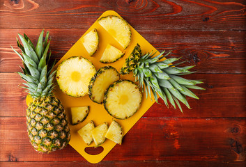 fresh ripe tropical pineapple cut into slices on a yellow rackside lying on a wooden table