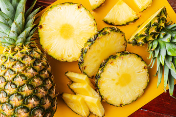fresh ripe tropical pineapple cut into slices on a yellow rackside lying on a wooden table