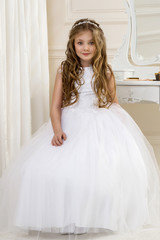 Portrait of cute little girl on white dress and wreath on first holy communion background church...