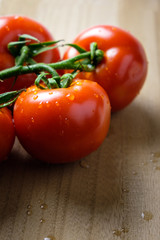 Tomatoes panicles with water drops on a wooden chopping board