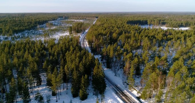 Aerial, drone shot, revealing a car, parked on the side of a snowy forest road, on a sunny, winter evening, in Tejio national park, in Varsinais-suomi, Finland