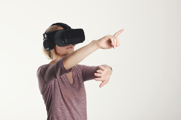 A young woman is wearing virtual reality glasses and reaching for something with his hands