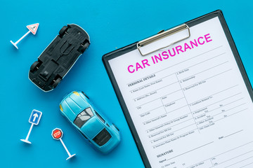 Car insurance concept with form, car toys on blue background top view