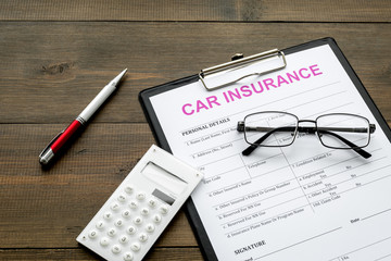 Car insurance form near glasses, calculator, pen on dark wooden background