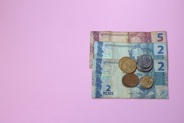 Pile of brazilian money low value on pink background with copy space for text. Saving money in Brazil is hard for millennials. How to proceed?