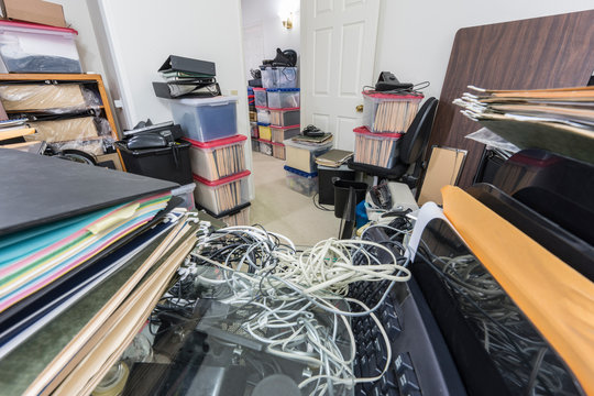 Messy back office desk with files, boxes, clutter, old equipment and miscellaneous storage.  