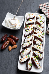Dates stuffed with cream cheese and almonds on black stone background