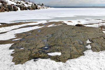 Rocky coast of snow-covered island of Helsinki archipelago, Finland