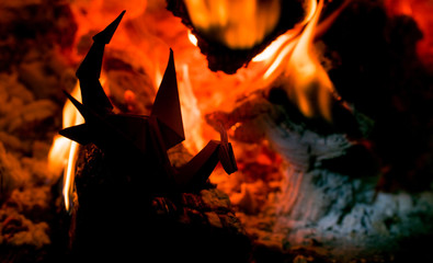 Origami paper toy dragon on the background of burning fire