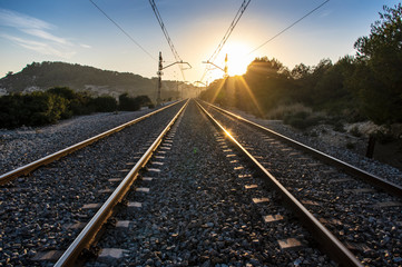 Fototapeta na wymiar Train tracks at sunset with bright sun and metal reflections