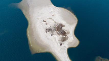 Little sand island in blue sea with lot of bold tress , areal view 