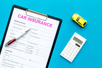 Car insurance concept with form, car toy and pen on blue background top view