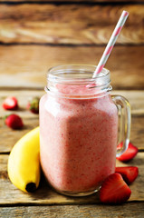 Strawberry banana smoothie on a dark wood background