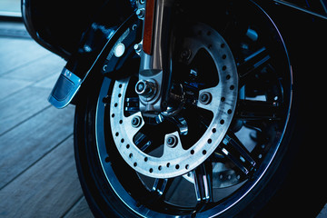 front fork of a motorcycle with a front wheel, brake disc, brake cylinder. Close up. Soft focus