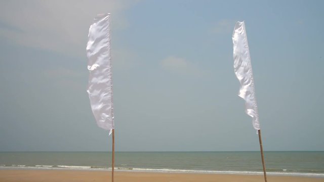 White beach flags flapping in the wind, empty tropical beach scene