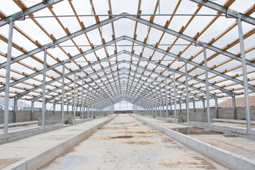 The frame of the roof of the new barn for cows. Construction of a new barn. Wooden beams on a metal frame. Construction of agricultural buildings.