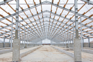 The frame of the roof of the new barn for cows. Construction of a new barn. Wooden beams on a metal frame. Construction of agricultural buildings.