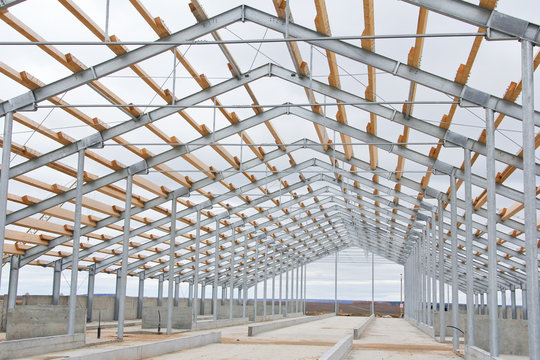 The construction of the new barn. Wooden beams on a metal frame. Construction of agricultural buildings. The construction of the barn. Agriculture