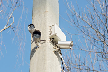 Compact video surveillance cameras on support post in public areas on blue sky. Security cameras on...