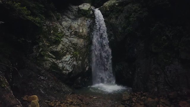 hd drone dolly backward, zooming out from waterfall, rocky place, dark light, in Turkey
