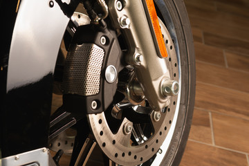 front fork of a motorcycle with a front wheel, brake disc, brake cylinder. Close up. Soft focus