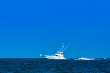 White luxury yacht sport fisher with breaking bow wave.