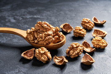 Organic walnut in wooden spoon on black table, with copy space.