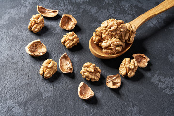 Walnut in wooden spoon on black table, with copy space. Top view.