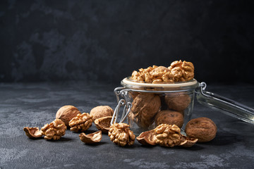 Walnut in an open glass jar on black  background, close-up.