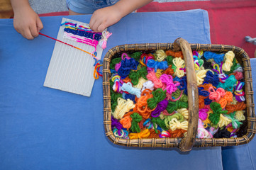 Child girl learning to use cardboard weaving loom