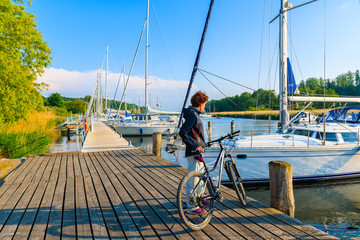 SEEDORF PORT, RUGEN ISLAND - MAY 27, 2018: Woman with bicycle standing in beautiful marina on coast...