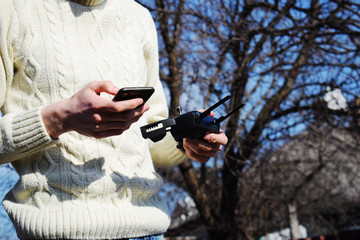 Remote control and smartphone in male hands. A man holding a transmitter and piloting some...
