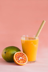 Glasses of mango, orange juice on pink background.