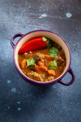 Beef stew with vegetables on grunge blue background