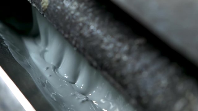 Extreme closeup of bubbling light green-grey paint in an old and grungy wallpaper printer