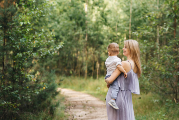 Happy young family spends time together in nature. Sweet mother with baby