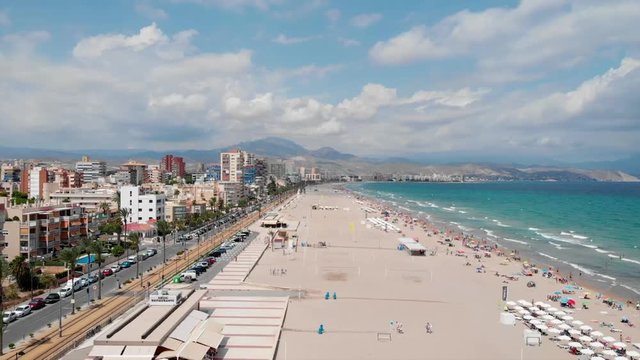 Sunny high aerial shot of San Juan beach with mountains in the background recorded mid-day