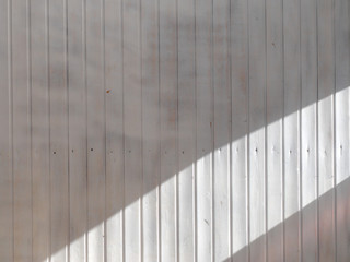 Wooden weatherboard painted white with a wide stripe of sunlight. Background and texture.