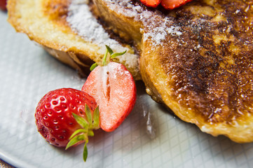 French toast with strawberries and maple syrup. Gray background, side view, close-up