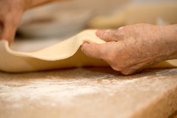 hands of an old woman roll out the dough close-up macro