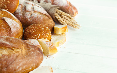 Assortment of baked bread on wooden table background