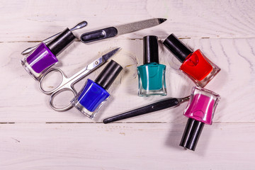 Different manicure tools and nail polishes on wooden table. Top view